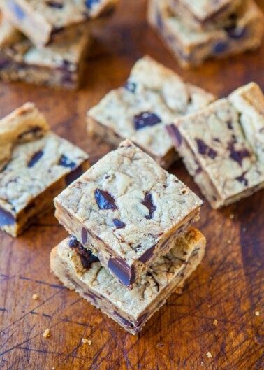 Chocolate chip cookie bars stacked on a wooden surface.