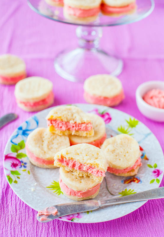 sandwich cookies on a floral plate. More cookies sit on a cake stand in the background. 