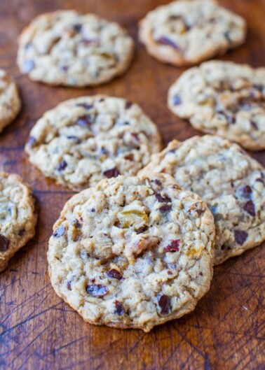 Freshly baked chocolate chip cookies with nuts cooling on a wooden board.