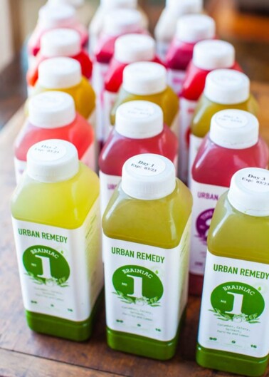 Rows of colorful bottled juices labeled "urban remedy" arranged on a wooden surface.