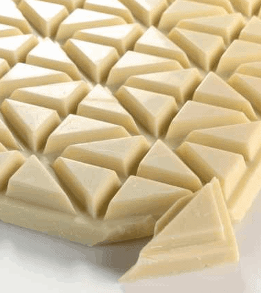 An array of geometrically shaped white chocolate pieces arranged in a pattern.