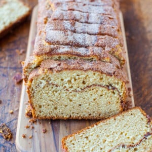 Freshly baked cinnamon bread on a wooden cutting board, sliced and dusted with sugar.