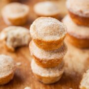 Stack of sugared doughnuts on a wooden surface.