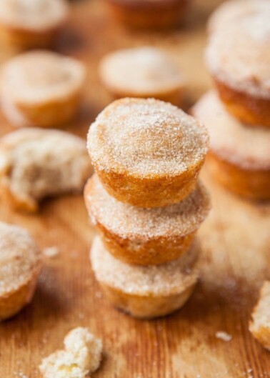 Stack of sugared doughnuts on a wooden surface.