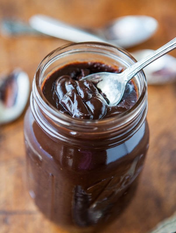 scooping homemade hot fudge out of jar with spoon