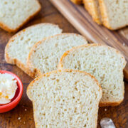 Sliced white bread on a wooden cutting board with a butter dish and knife.