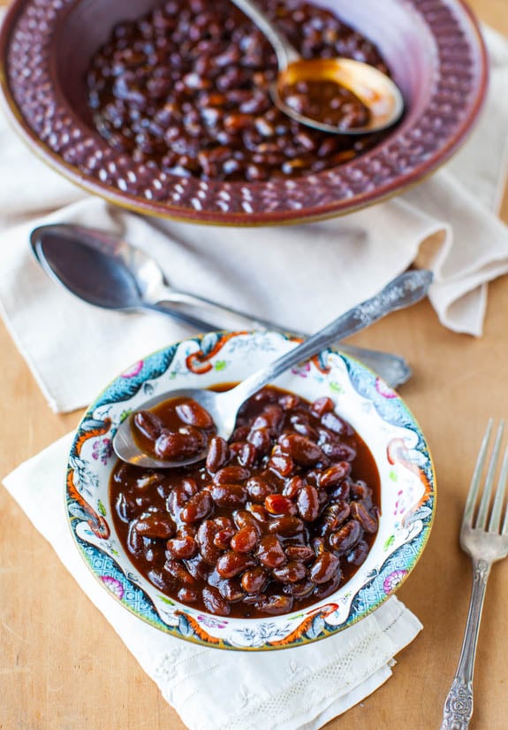 two dishes of slow cooker baked beans on white towels