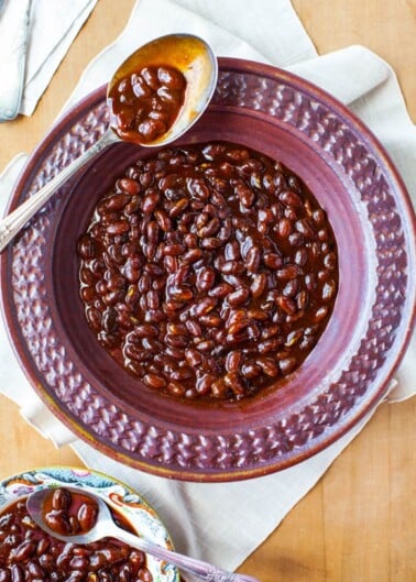 A bowl of baked beans served with a spoon.