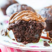 A chocolate muffin with a dollop of melting chocolate spread on top, placed on a floral plate.