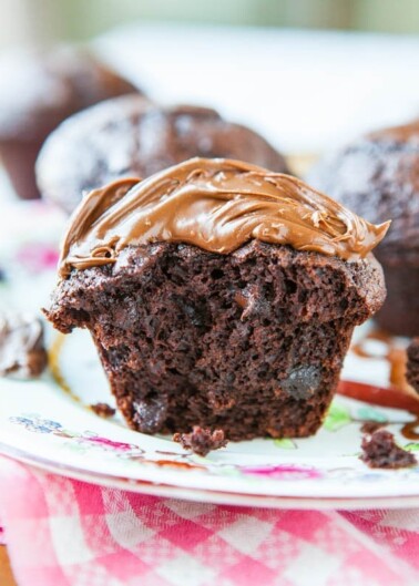 A chocolate muffin with a dollop of melting chocolate spread on top, placed on a floral plate.