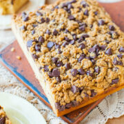 A freshly baked chocolate chip crumb cake on a wooden board.