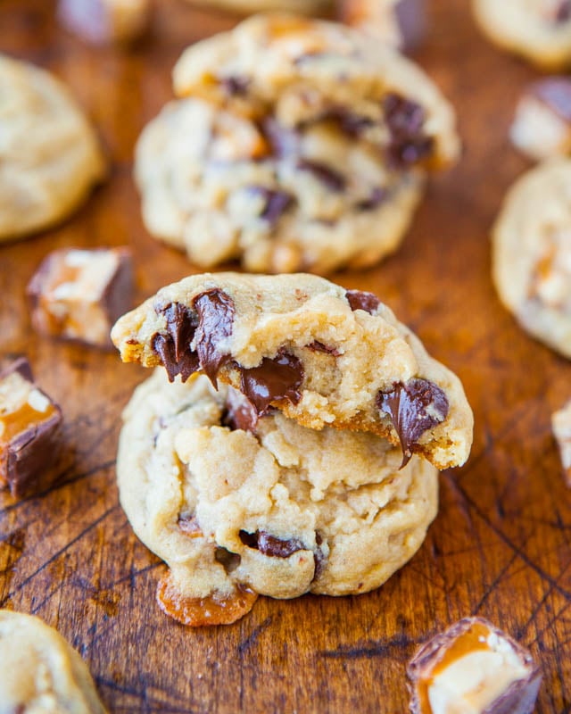 Soft and Chewy Snickers Chocolate Chip Cookies with one half showing gooey chocolate 