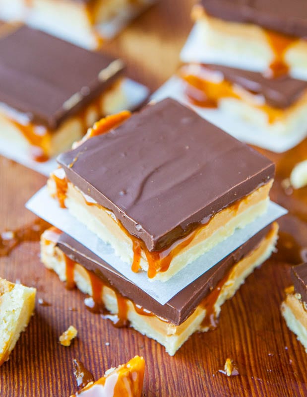 Stacked Peanut Butter Caramel Twix Bars separated by parchment paper