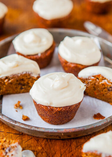 Freshly baked carrot cupcakes with cream cheese frosting on a serving tray.
