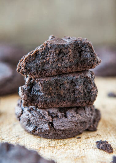 Three chocolate cookies stacked on a wooden surface.