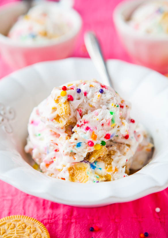 golden oreo ice cream in white bowl with a spoon topped with sprinkles