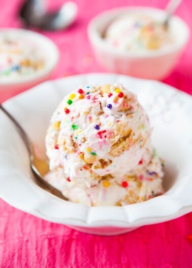 Scoop of colorful sprinkle-dotted ice cream on a spoon, with more in a bowl in the background.