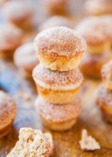 Stack of sugar-coated doughnut holes with more scattered in the background.