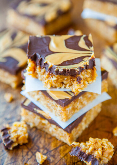 Stack of homemade peanut butter bars with chocolate topping on a wooden surface.
