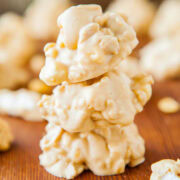 A stack of white chocolate-covered peanut clusters on a wooden surface.