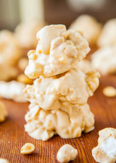 A stack of white chocolate-covered peanut clusters on a wooden surface.