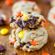Stacked chocolate chip cookies with colorful candy pieces on a wooden surface.