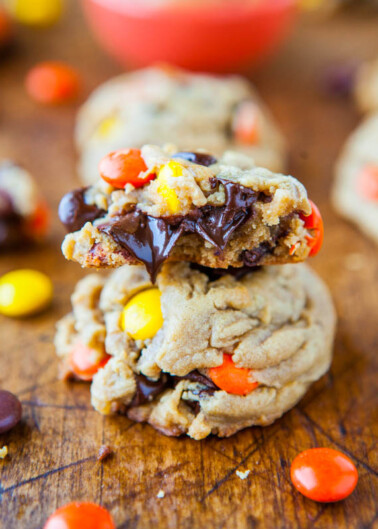 Stacked chocolate chip cookies with colorful candy pieces on a wooden surface.