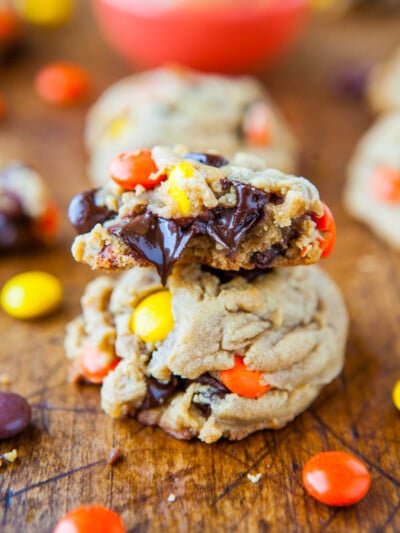 Stacked chocolate chip cookies with colorful candy pieces on a wooden surface.