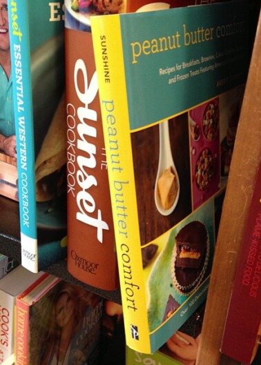 A row of cookbooks on a shelf with titles focused on various culinary themes.