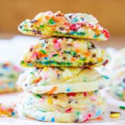 A stack of colorful sprinkle-filled sugar cookies on a plate.