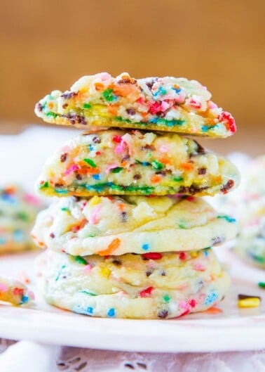 A stack of colorful sprinkle-filled sugar cookies on a plate.