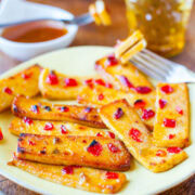 Grilled banana slices with honey and chili flakes on a yellow plate.