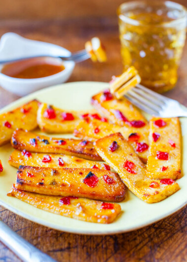 Grilled banana slices with honey and chili flakes on a yellow plate.