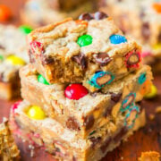 A stack of colorful candy-studded blondie bars on a wooden surface.