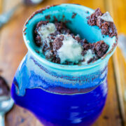 A blue ceramic mug filled with mint chocolate chip ice cream on a wooden surface.