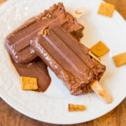 Chocolate popsicles on a white plate with small bite-sized pieces of biscuit.