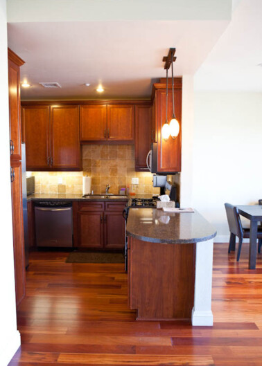 A modern kitchen with wooden cabinets, granite countertops, and hardwood flooring.