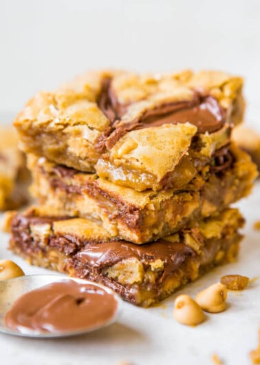 Stack of peanut butter chocolate chip blondies on a white surface.
