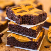 Stack of peanut butter swirl brownies on parchment paper.