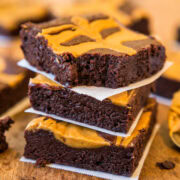 Stack of peanut butter swirl brownies on parchment paper.