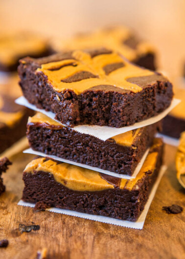 Stack of peanut butter swirl brownies on parchment paper.
