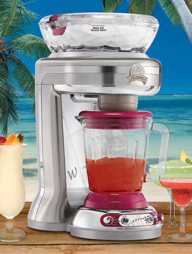 Blender on a beachside countertop with tropical drinks.