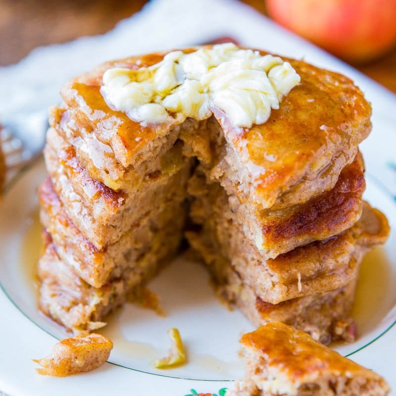 A stack of apple pancakes with syrup and a pat of butter on top.