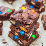 Stack of homemade brownies with colorful candy pieces and chocolate chips on top.