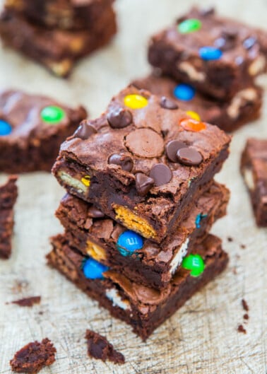 Stack of homemade brownies with colorful candy pieces and chocolate chips on top.