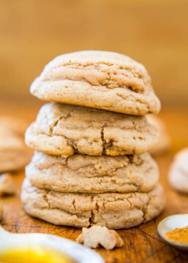 A stack of freshly baked peanut butter cookies on a wooden surface.