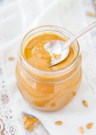 A jar of creamy peanut butter with a spoon inside it.