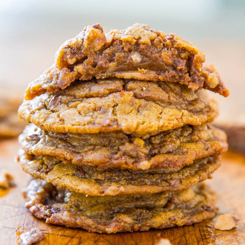 A stack of freshly-baked cookies on a wooden surface.