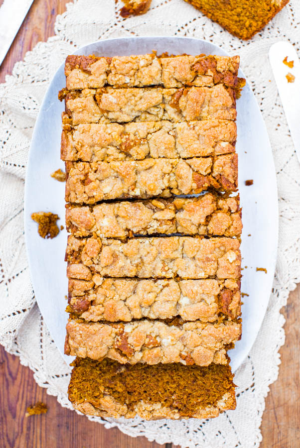 overhead view of sliced loaf of vegan pumpkin bread with streusel topping on a white platter