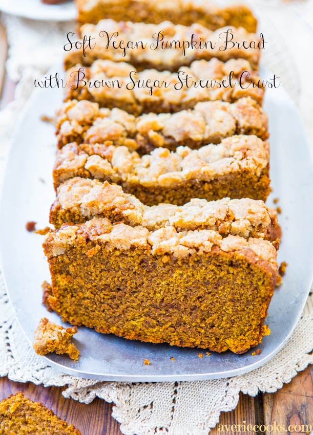 sliced loaf of vegan pumpkin bread with streusel topping on a white platter